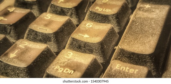 Macro shot of a very old computer keyboard. Abrasion and a layer of dust are visible on the keyboard.