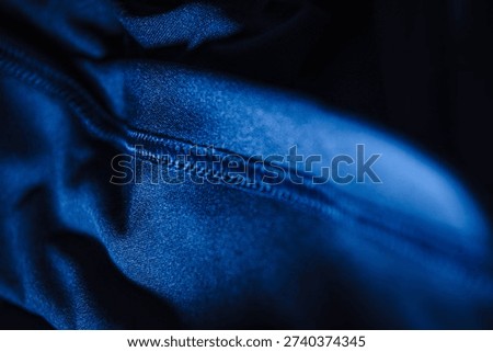 Macro shot of vibrant blue technical sports fabric featuring a professional flatlock or overlock stitched seam. High-quality textile background for athletic apparel and modern fitness wear design.