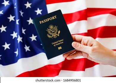 Macro shot of woman's hand holding the latest version of United States of America citizen Passport with biometric ID chip. Person identification document. Close up, copy space, USA flag background. - Powered by Shutterstock