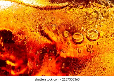 macro soft drink texture,Close up view of ice cubes in dark cola background. Textures of sweet summer cold drinks with foam and macro bubbles on Fizzing glass wall. or float to the top of the surface