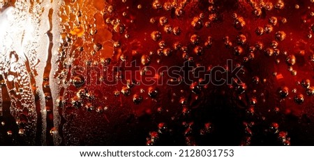 macro soft drink texture,Close up view of ice cubes in dark cola background. Textures of sweet summer cold drinks with foam and macro bubbles on Fizzing glass wall. or float to the top of the surface