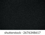 A macro texture background showing a close-up of a black porous, non-slip foam surface. A dark abstract background.