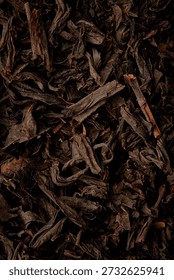 Macro texture of premium loose leaf Chinese black tea with golden tips. High-quality fermented tea background. Top view, close-up.