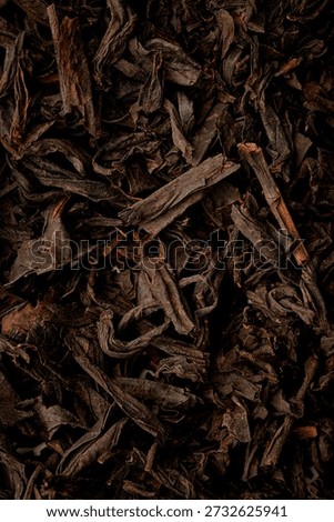Macro texture of premium loose leaf Chinese black tea with golden tips. High-quality fermented tea background. Top view, close-up.