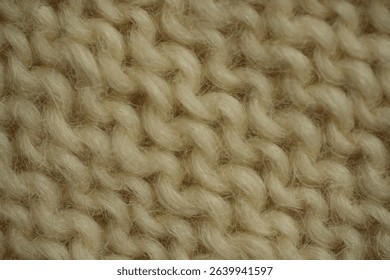 macro texture of white wool knitted fabric. Handcrafted with knitting needles, the soft yarn forms a cozy and natural background. Ideal for textile design, winter themes, handmade crafts, or slow fash