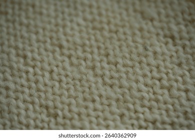 macro texture of white wool knitted fabric. Handcrafted with knitting needles, the soft yarn forms a cozy and natural background. Ideal for textile design, winter themes, handmade crafts, or slow fash