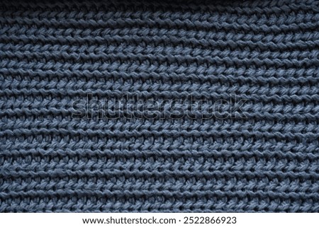 macro texture of woolen dark gray crocheted sweater as background, close-up of gray crocheted front surface, woolen texture of woolen wool, knitted front surface