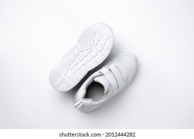 Macro Top View Two White Unisex Running Shoes, One Running Shoe Lies Sole Up Isolated On White Background.