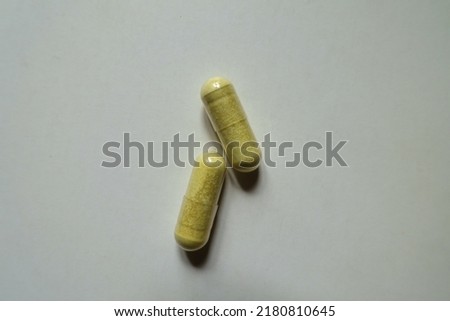 Macro of two yellowish green capsules of quercetin dietary supplement