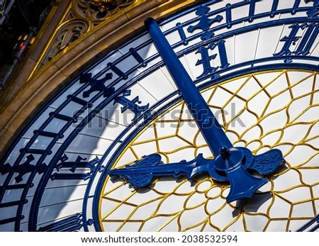 Macro view of Big Ben clock face with blue hands and ornate gold detail capturing a precise moment in time; ideal for concepts of punctuality, deadline, schedule, London branding