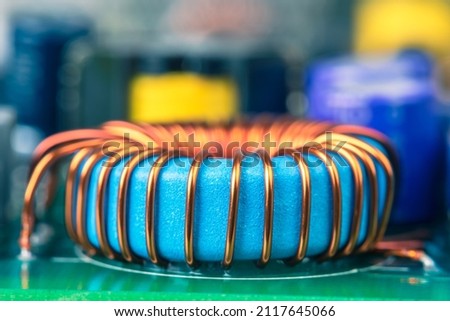 Macro view of electronic component, induction coil with copper wire winding on magnetic ferrite core on circuit board