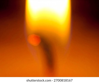 A macro view of a flame showing various shades of orange and yellow colors in a blurred and out of focus effect.