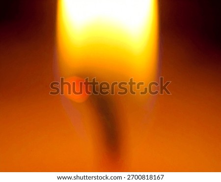 A macro view of a flame showing various shades of orange and yellow colors in a blurred and out of focus effect.