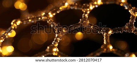Macro view of a luminous hexagonal lattice, resembling a molecular structure, adorned with sparkling golden fairy lights against a dark background.