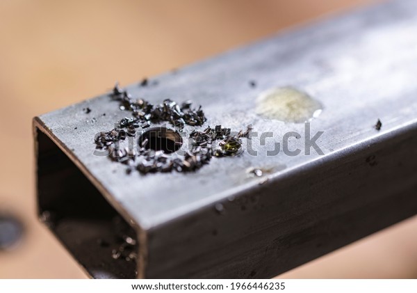 Macro view of the metal shavings and an oil drop on\
the top of the metal bar