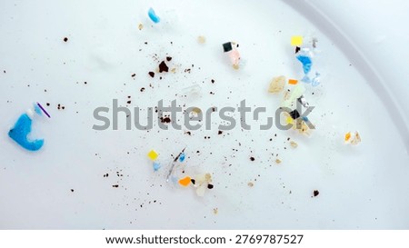 Macro view of microplastic pieces scattered on a Petri dish. A collection of plastic fragments and sediment highlights the global ocean pollution. Micro plastic particles and synthetic debris