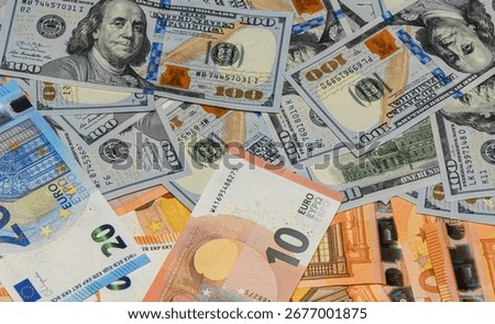 Macro view of scattered 100 USD bills and 50 EUR banknotes on a table, creating a textured money background suitable for finance, business, and investment.