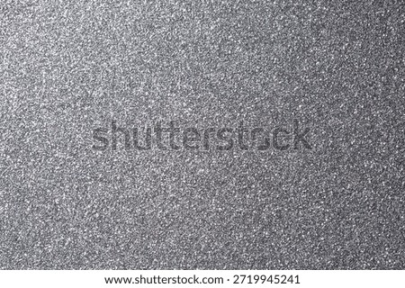 Macro view of silver glitter surface with reflective sparkle and fine texture. Perfect for festive, glamorous, or decorative design projects.