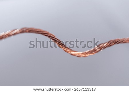 Macro view of a single twisted bare copper wire on a smooth background.