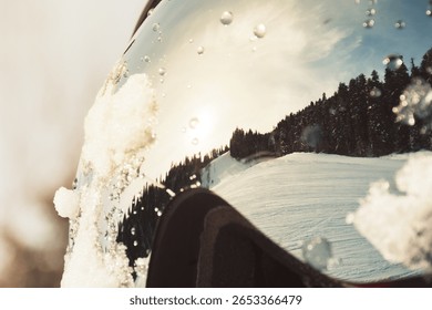 Macro view ski resort reflected in ski goggles with water drops, pine forest under clear winter sky, concept extreme sport, safety, perspective.