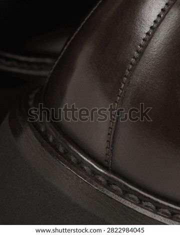 Macro view of the stitched welt, heel and leather upper of a brown ankle boot.