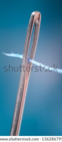 Macro view of thread going through the eye of a needle.