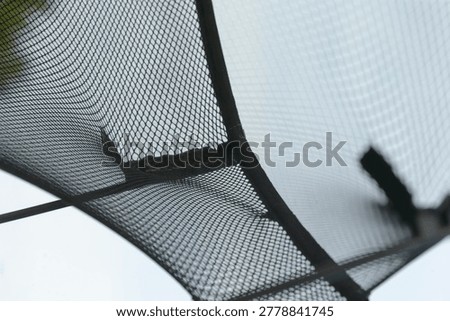 Macro view trampoline net patched corner with adhesive tape and mended stitching, outdoor repair narrative, handson restoration, afternoon light, practical maintenance mood,