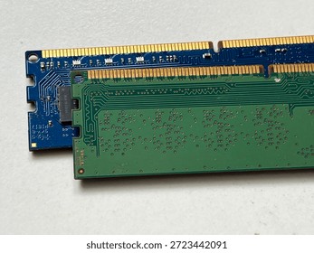 Macro view of two computer RAM memory modules on a white background. Detailed shot of green and blue printed circuit boards (PCB) showing gold contact pins and electronic traces of DDR desktop memory.