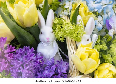 Macro view of two white Easter bunnies in a spring flower bouquet