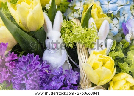 Macro view of two white Easter bunnies in a spring flower bouquet