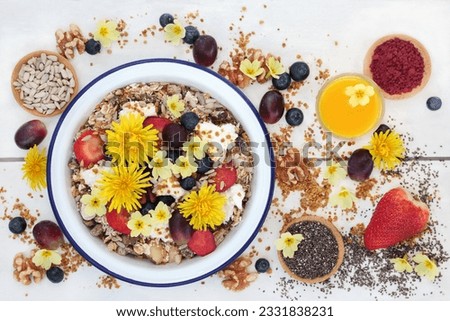 Macrobiotic health food for breakfast concept with granola, edible flowers, acai berry powder, pollen grain, berry fruit, chia seed and nuts with foods high in protein, omega 3, anthocyanins, antioxid
