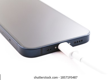 Macrophotography of Apple iPhone 12 mini blue front view isolated on white background. Charging modern smartphone. Unpacking purchase concept.