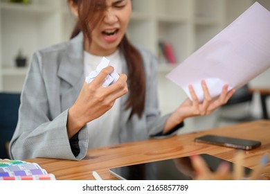 Mad angry asian businesswoman or female boss crumpling a document paper, yelling in the office, unsatisfied with her work project. Cropped image, Crumpled paper in woman hand.