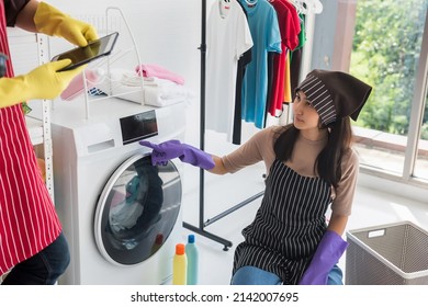 Mad Asian Wife Or Girlfriend Work On Laundry Machine While She Look At Her Lazy Boyfriend Or Husband Playing Smartphone. She Upset And Feel Angry To Do Housework Alone.