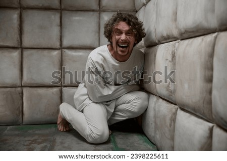 Mad crazy man patient wearing straitjacket laughing terrifying