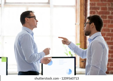 Mad male colleagues have disagreement in office arguing on work issues, furious millennial employee point at coworker blaming for mistake or failure, businessman accuse partner disputing at workplace