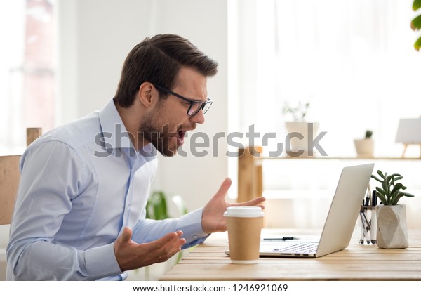 Mad male worker lose temper scream loudly having\
computer problems or virus attack, furious man shout experience\
laptop breakdown or data loss while working, angry employee get\
error message on pc