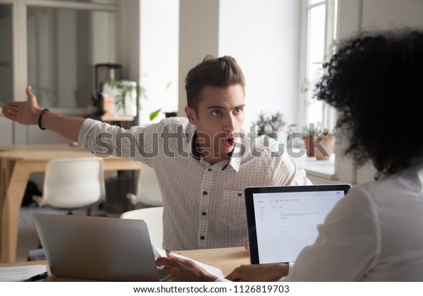 Mad male worker yelling at female colleague asking\
her to leave office, multiracial coworkers disputing during\
business negotiations, employees cannot reach agreement, blaming\
for mistake or crisis
