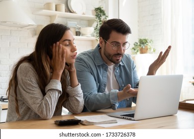 Mad millennial couple frustrated with slow Internet connection paying bills online in kitchen, confused young husband and wife angry with unexpected error mistake using internet banking on computer