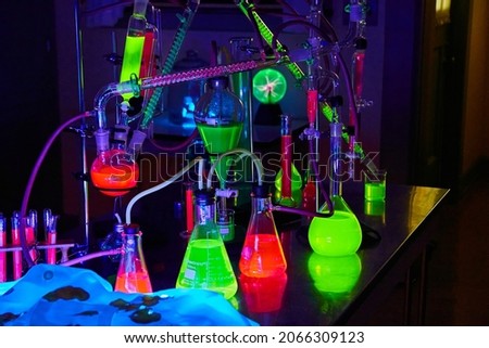 Mad scientist chemistry lab in dark with glowing green and red chemicals