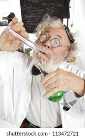 Mad Senior Scientist In Lab Concentrates On Pouring Green Liquid Into Beaker. Frizzy Grey Hair, Round Glasses, Lab Coat, Blackboard, Vertical, High Key, Copy Space.