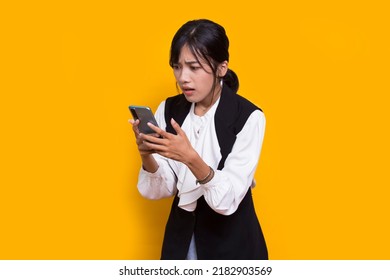 Mad And Shock Young Asian Beautiful Woman Using Mobile Phone Isolated On Yellow Background