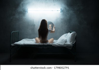 Mad woman with mirror sitting in bed, insomnia