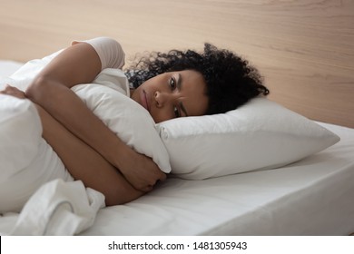 Mad Young African American Woman Wake Up Lying In Bed Feel Down Upset Thinking Of Personal Problem, Angry Black Millennial Girl Awake From Rest In White Bedroom. Bad Morning Sleep Concept