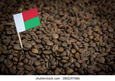Madagascar flag sticking in roasted coffee beans. The concept of export and import of coffee