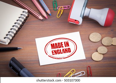 Made in England stamp. Wooden office desk with stationery, money and a note pad