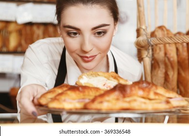 Made with love. Beautiful young female baker placing freshly baked croissants to the showcase - Powered by Shutterstock