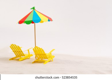 Made Of Paper Umbrella And Beach Chair On The Sand. White Background