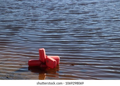 Made of plastic bottles red buoy on the Baltic shore in shallow water, with more water in perspective.