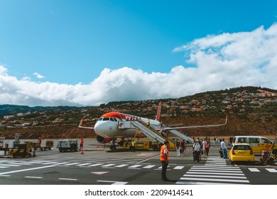 Madeira Island, Portugal - 2022, August 26th - Passangers Walking Out An Easyjet Airplane In The Cristiano Ronaldo International Airport With Houses In The Back And Staff In The Ground